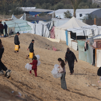 Palestinos deslocados pela guerra carregam garrafas vazias para um caminhão de água de MSF em Tal Al-Sultan, sul de Gaza. Janeiro de 2024. © MSF