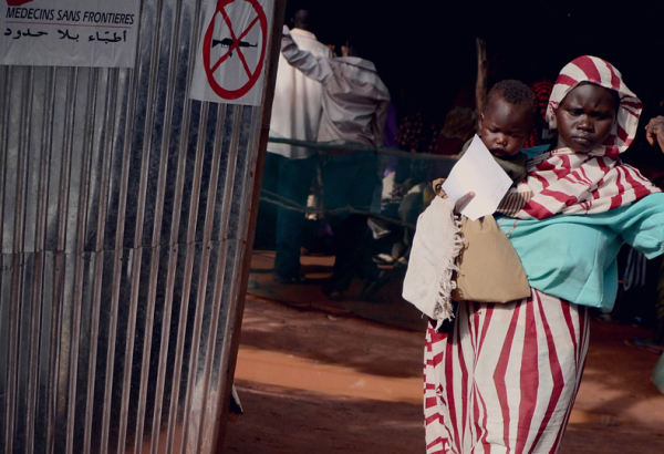 Uma mulher está a caminho da uma clínica de MSF no campo de refugiados de Yida, no norte do Sudão do Sul, para levar seu filho a uma consulta médica. Hoje, são 70 mil refugiados em Yida. A maioria deles são das montanhas de Nuba, no sul do Sudão, de onde eles fugiram dos conflitos. Hoje, MSF oferece assistência médica à população e realizada, em média, 300 consultas por dia. Muitos dos refugiados estão sofrendo com malária e infecções respiratórias por conta das difíceis condições de vida durante a estação chuvosa.       